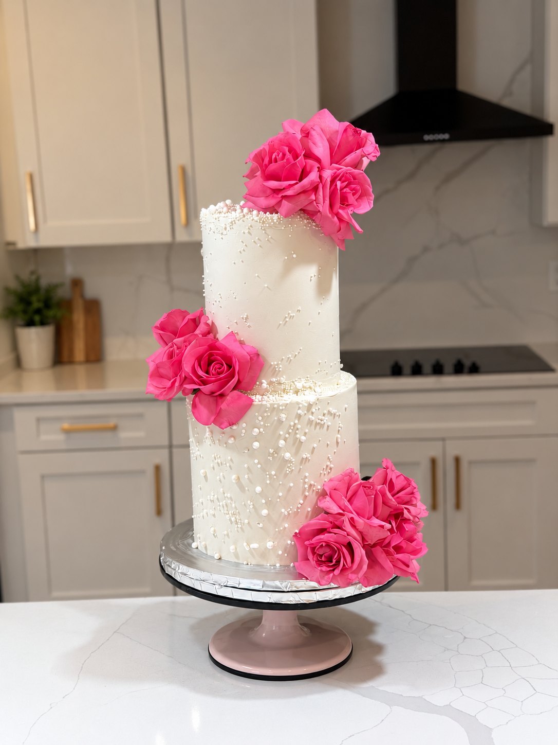 White two-tier buttercream cake with pearl details and bright pink roses by LoveLeigh Confections